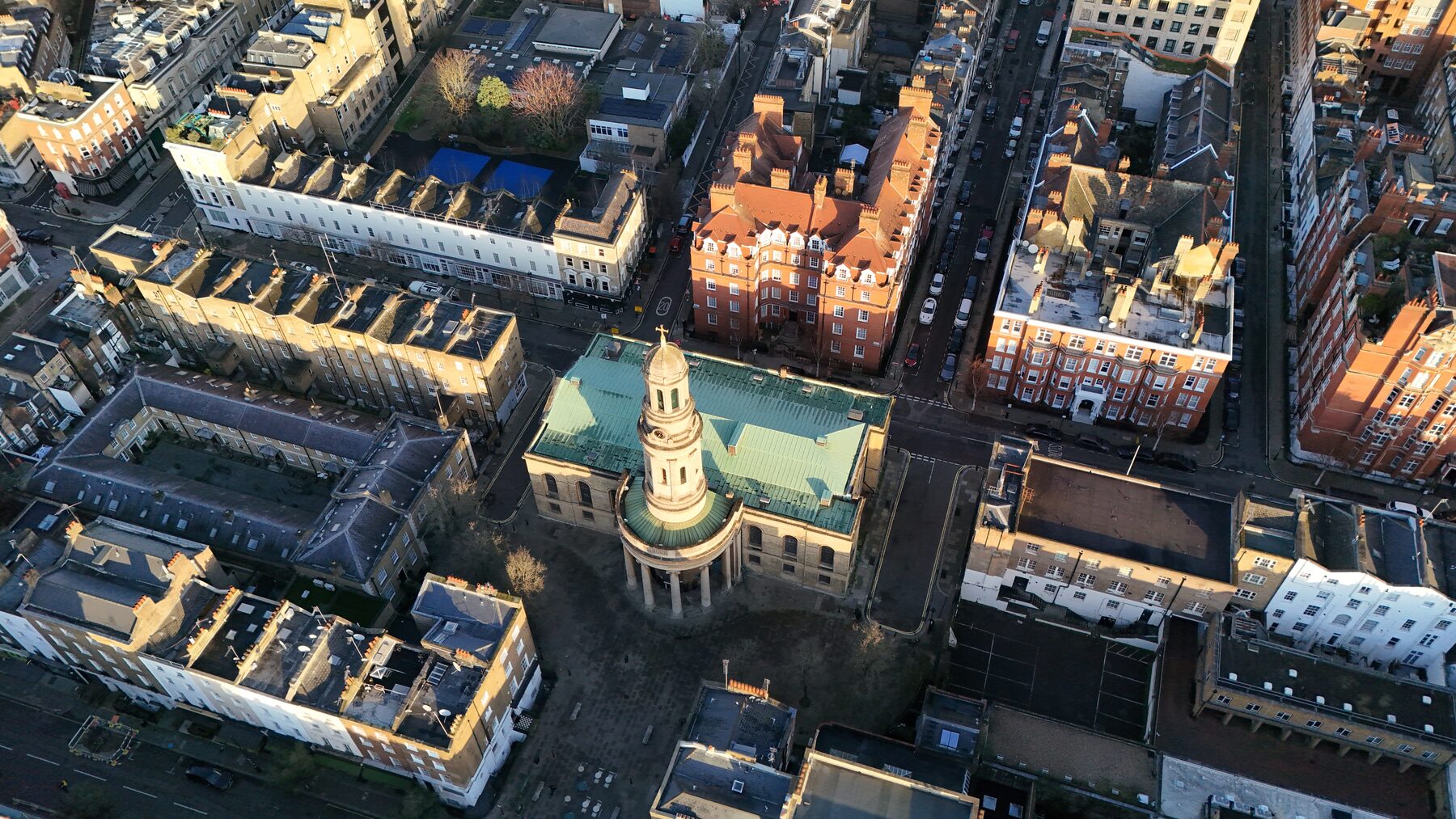 Aerial of St Mary's church and its green copper roof among Marylebone streets in low morning sun